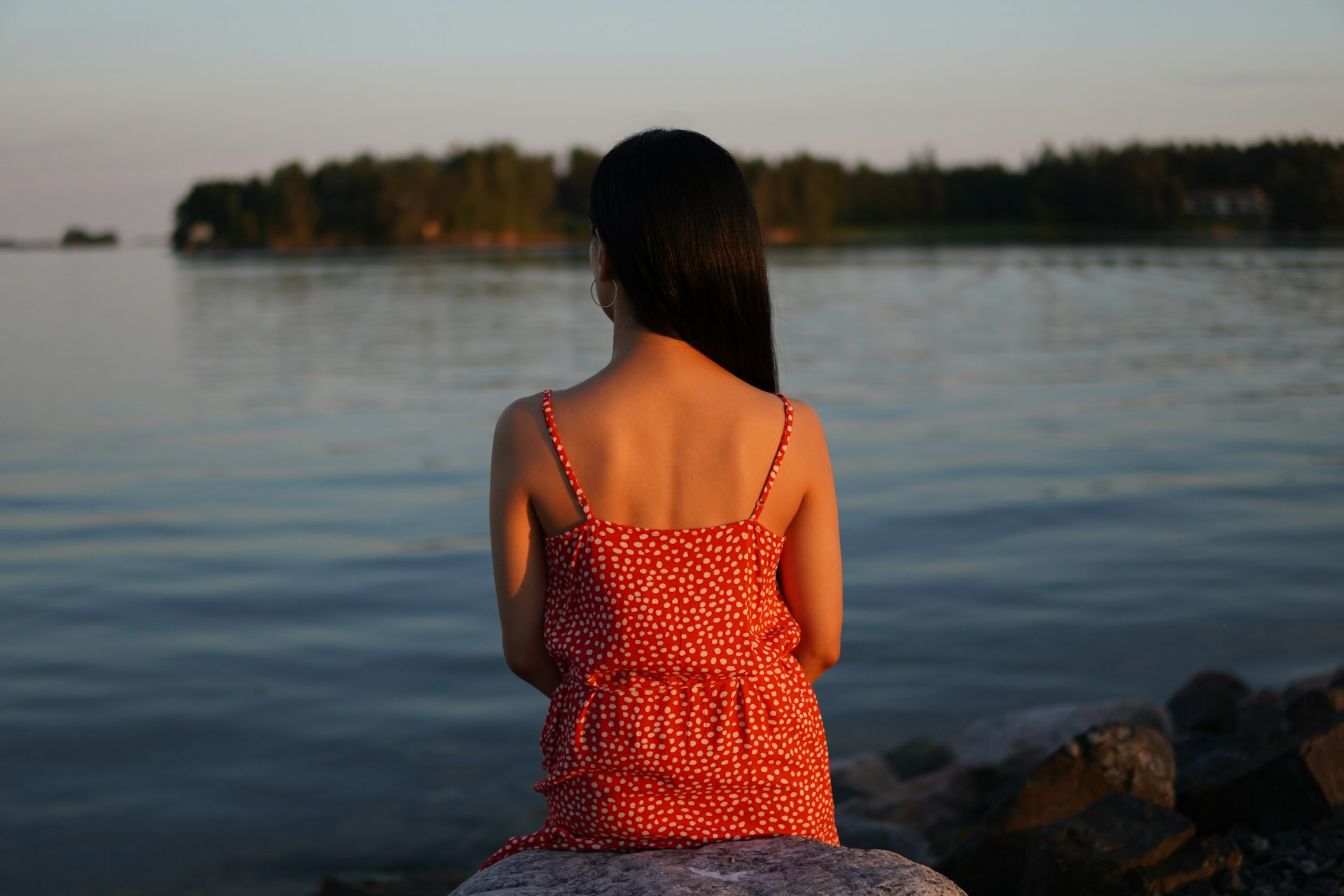 Woman looks out at the water at sunset.